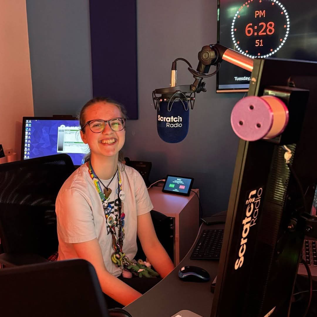 Amber sitting in a radio studio, with a Scratch Radio branded microphone